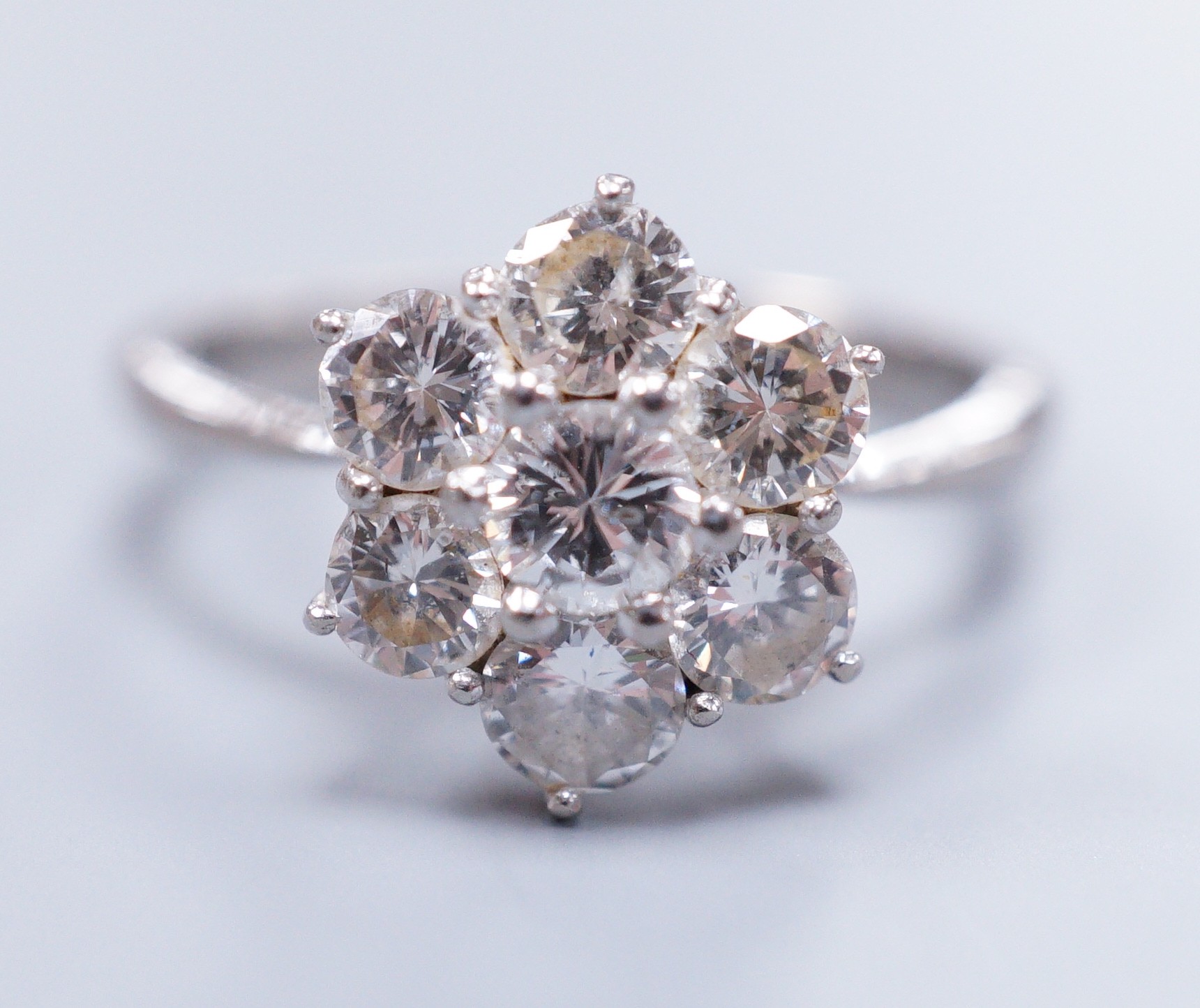 An 18ct white gold seven stone diamond cluster ring, size M, gross 4.1 grams